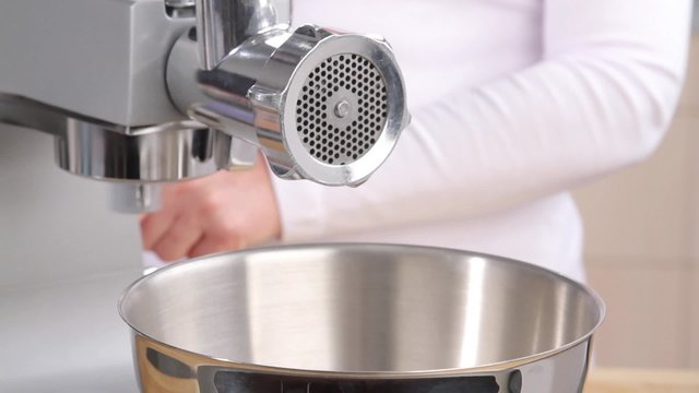 Putting minced meat and vegetable mixture through mincer