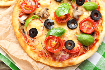 Tasty pizza with vegetables and basil on table close up