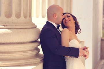 Bride and groom embracing near columns