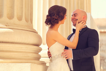 Bride and groom embracing near columns