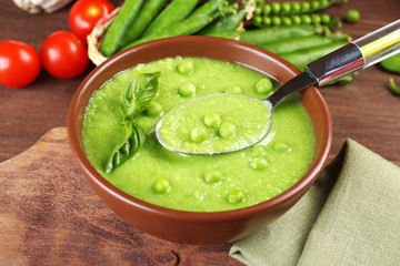 Tasty peas soup and cherry tomatoes on table close up