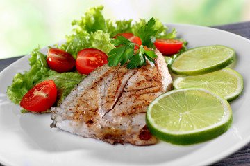 Dish of fish fillet with salad and lime on plate close up