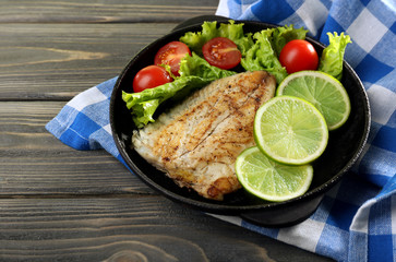 Dish of fish fillet with salad and lime on table close up