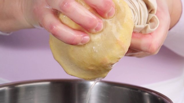 Squeezing out bag containing orange pith and pips