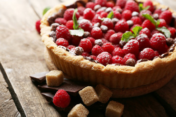 Tart with fresh raspberries, on wooden background