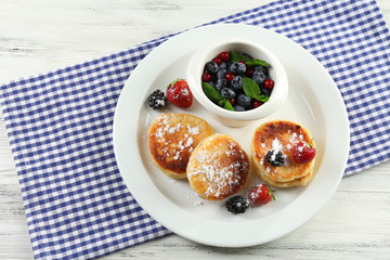 Fritters of cottage cheese with berries in plate on table, closeup
