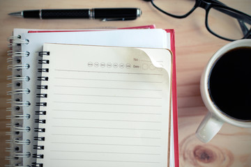 Fototapeta na wymiar Cup of coffee with blank notebook on wooden desk