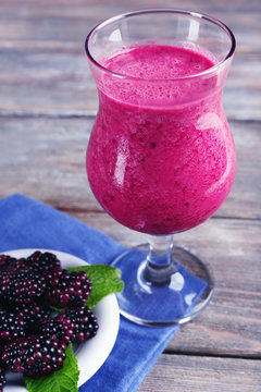 Glass of blackberry smoothie on wooden table, closeup