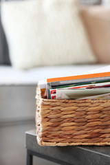 Magazines in basket on table in living room, close up