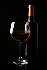 Bottle and glass of wine isolated on black