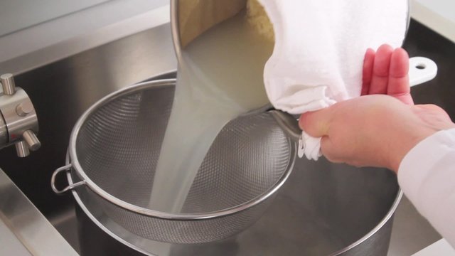 Cooked orzo pasta being poured into a sieve and quenched