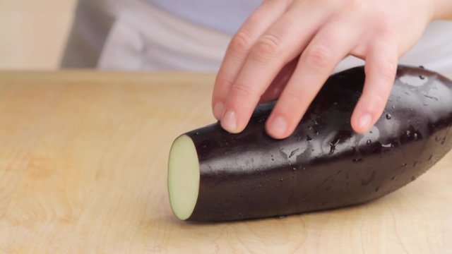 An aubergine being cut lengthways