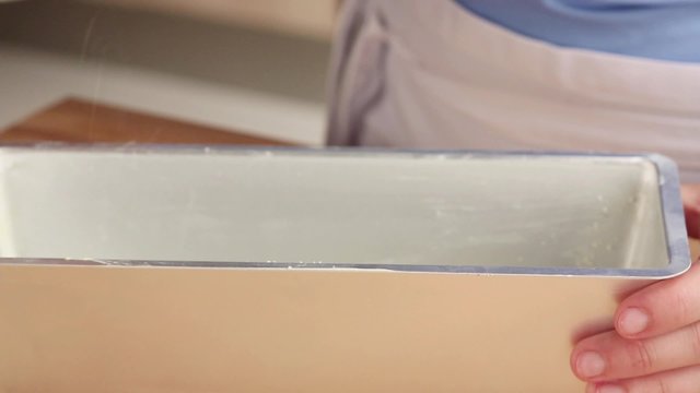 Breadcrumbs being sprinkled into a buttered loaf tin