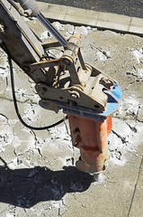 large jackhammer destroying pavement of a city street