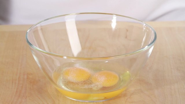 Beaten egg being seasoned with salt and pepper
