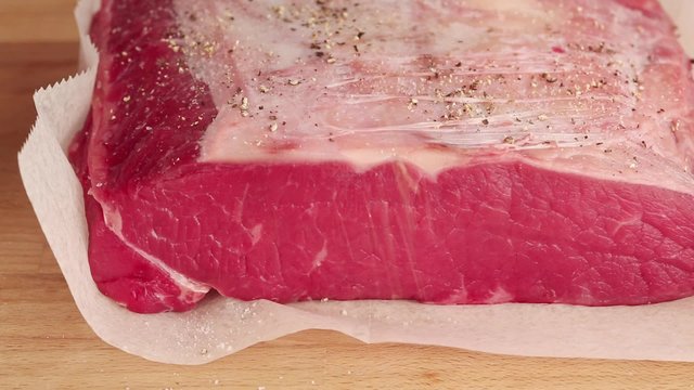 Beef being seasoned with pepper
