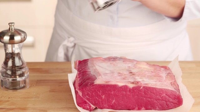 Beef being seasoned with salt