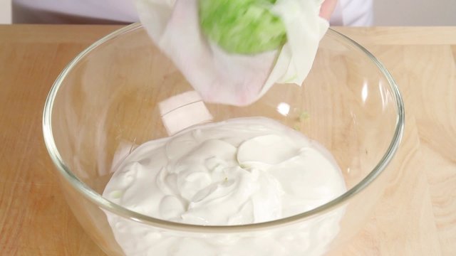 Wrung out cucumber being added to yogurt