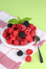 raspberries and blackberries on a plate light green background
