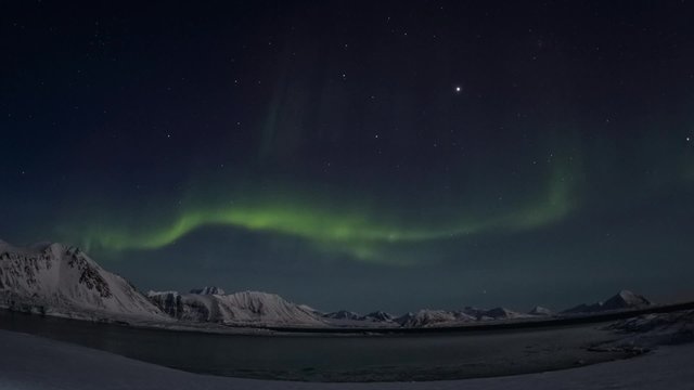 Winter in Arctic. Starry sky in the polar night. Northern Lights over glacier.
