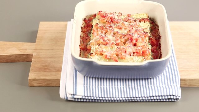 Basil being scattered over gratinated cannelloni