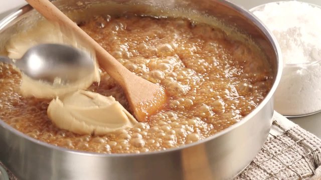 Peanut butter fudge being made: peanut butter being stirred into milk caramel