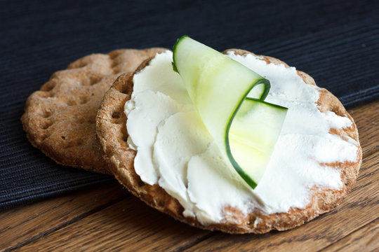Two round rye crispbreads on wood with black napkin. Top one spr