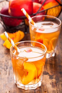 homemade ice tea with peach slices in glasses with straws