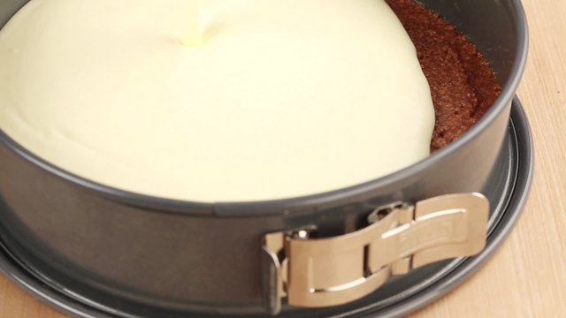 A cream cheese mixture being spread on a biscuit base