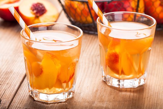homemade ice tea with peach slices in glasses with straws