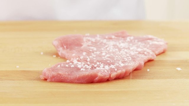 Seasoning veal escalope with salt and pepper