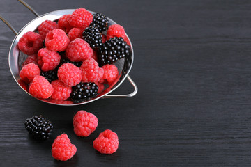 raspberries and blackberries in a bowl black background