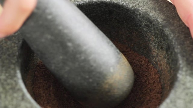 Crushing cumin in a mortar