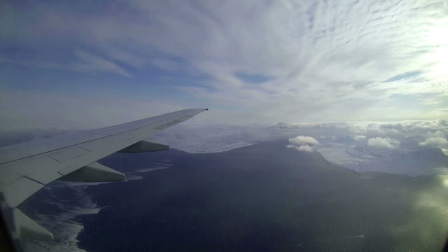 View of wing in the ocean and blue sky out from flying airplane.