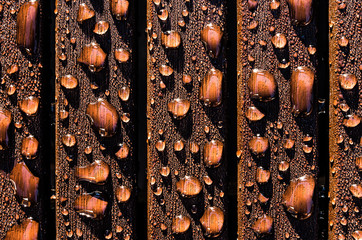 close up of glistening water drops on brown wooden slats