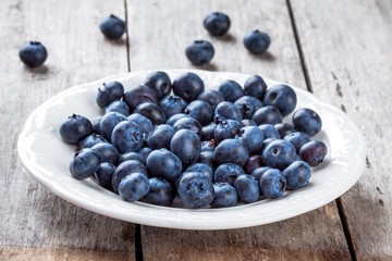 juicy fresh organic blueberries in a plate on a wooden table