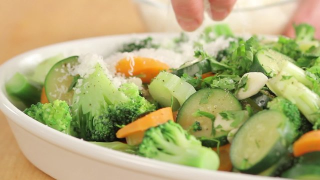 Scattering freshly grated parmesan over vegetables