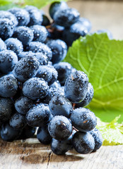Blue grapes with leaves on old wooden background, selective focu