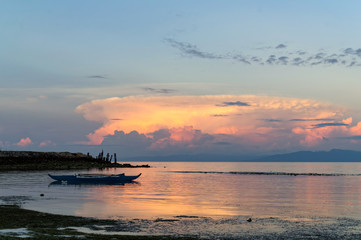 Fototapeta na wymiar Orange Clouds Reflecting Sunlight. Early morning view at the beach. A boat left on shallow waters