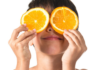 Child holding two slice oranges like glasses