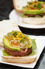 Homemade hamburgers with lettuce avocados, stir fried onions an peruvian yellow chili sauce