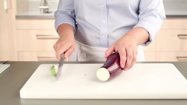 An aubergine being halved lengthways