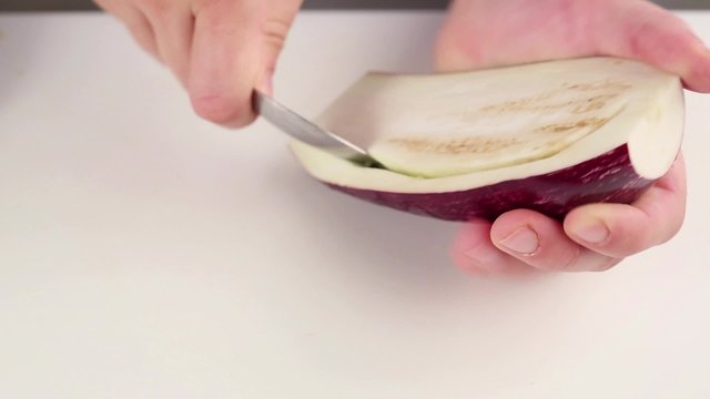Half an aubergine being hollowed out with a spoon