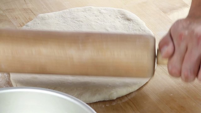 Pizza dough being rolled out and place in a deep pizza dish