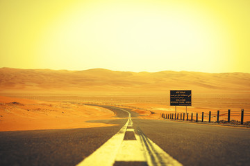 Winding black asphalt road through the sand dunes of Liwa oasis, United Arab Emirates