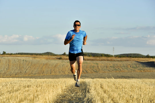 Sport Man With Sunglasses Running Outdoors On Straw Field Ground In Frontal Perspective