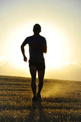 silhouette sport man running off road in countryside at summer sunset