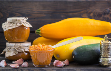 marrow paste in banks and in a bowl, garlic, and zucchini on the table
