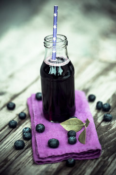 Blueberry juice in glass bottle, drinking straw