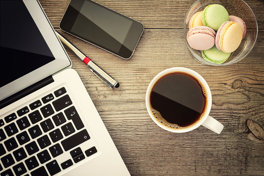 Laptop, cup of coffee and cookies on the wooden background